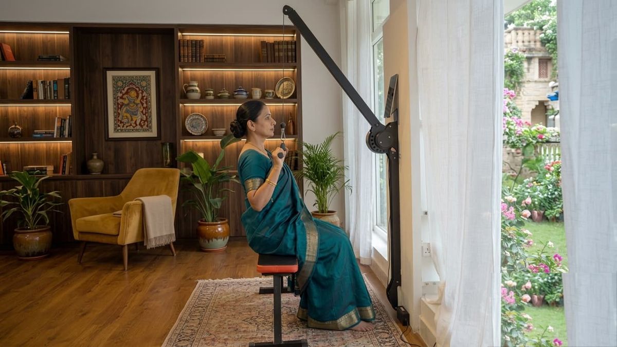 A Ferra member doing a seated pull-down on the wall-mounted machine in her sunlit living room